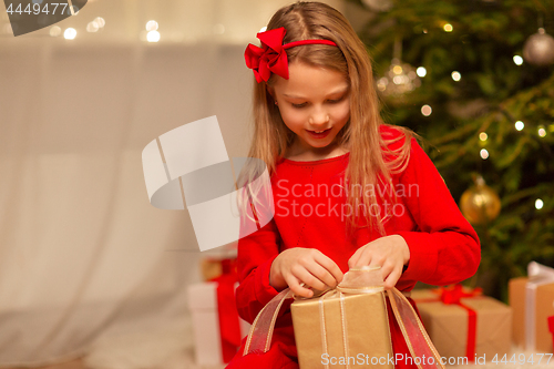 Image of smiling girl with christmas gift at home