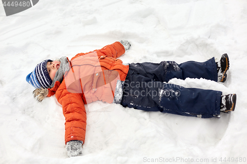Image of happy little boy making snow angels in winter