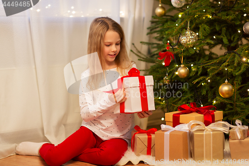 Image of smiling girl with christmas gift at home