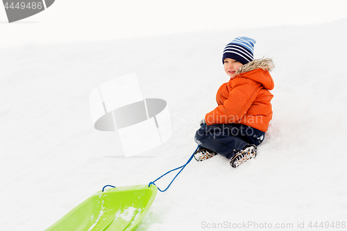Image of happy boy with sled on snow hill in winter