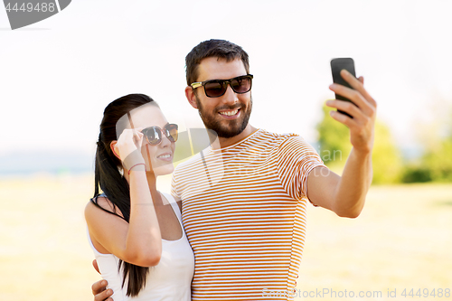 Image of happy couple taking selfie by smartphone in summer
