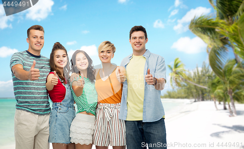 Image of friends showing thumbs up over tropical beach