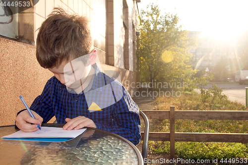 Image of Boy doing homework outdoors