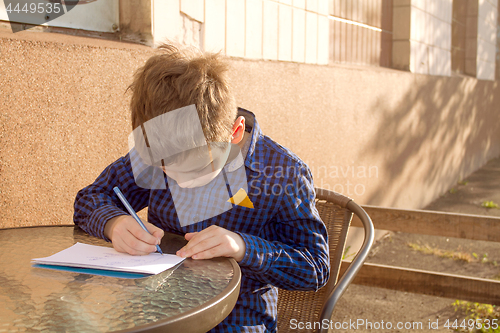 Image of Boy doing homework outdoors