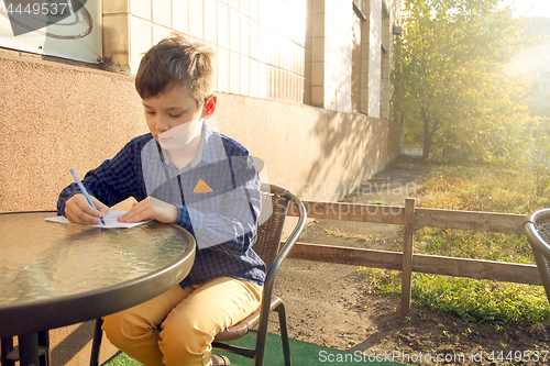 Image of Boy doing homework outdoors