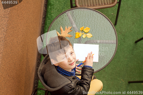 Image of Boy is doing homework outdoors