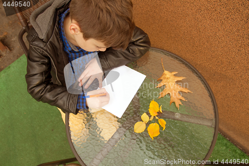 Image of Boy is doing homework outdoors