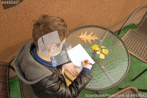 Image of Boy is doing homework outdoors