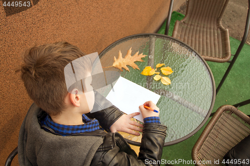 Image of Boy is doing homework outdoors