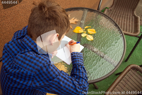 Image of Boy is doing homework outdoors