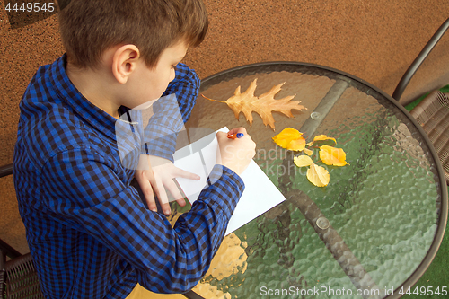 Image of Boy is doing homework outdoors