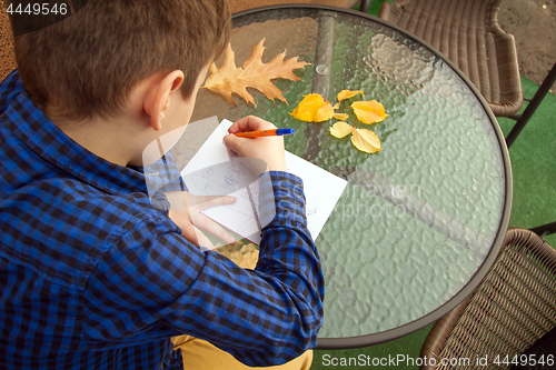 Image of Boy is doing homework outdoors