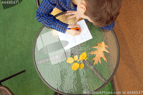 Image of Boy is doing homework outdoors