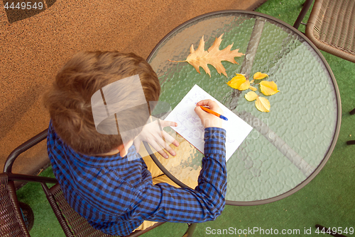 Image of Boy is doing homework outdoors