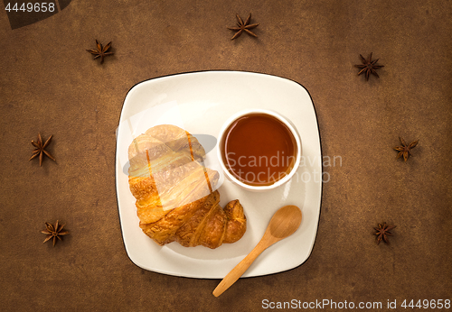 Image of Croissant and cup of tea on brown leather background