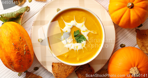 Image of Creamy pumpkin soup in bowl with herb