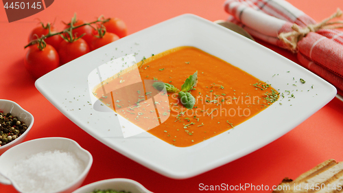 Image of Tomato soup in plate with green leaf