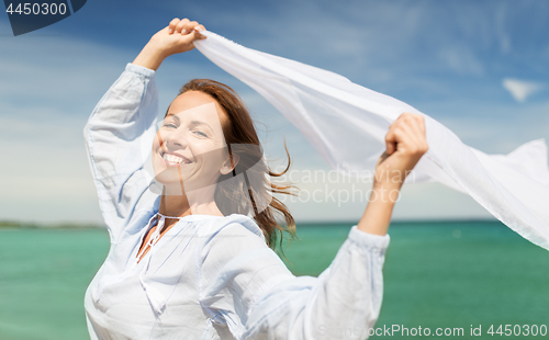 Image of happy woman with shawl waving in wind on beach