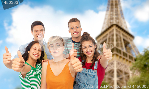Image of happy friends showing thumbs up over eiffel tower
