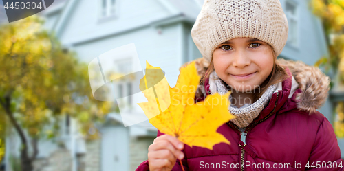 Image of close up of girl with autumn maple leaf over house