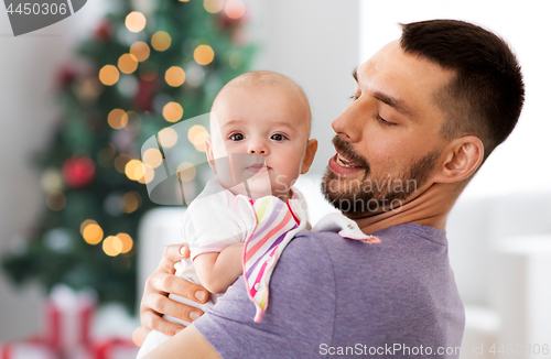 Image of father with baby daughter over christmas tree