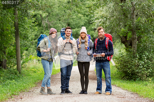 Image of friends or travelers hiking with backpacks and map