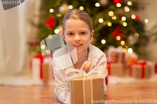 Image of smiling girl with christmas gift at home