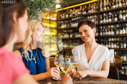 Image of happy women drinking wine at bar or restaurant