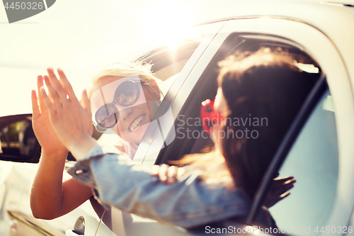 Image of happy teenage girls or women in car at seaside