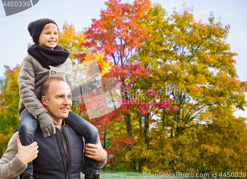 Image of happy father carrying son with autumn maple leaves