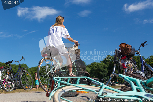 Image of Young beautiful blonde woman enjoying a bycicle ride on a sunny summer day in urban city park.