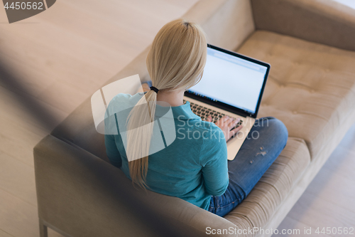Image of Young woman using laptop at home