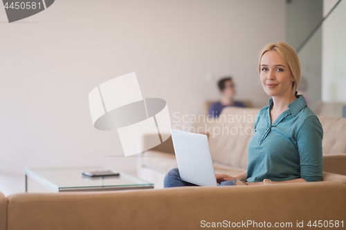 Image of Young woman using laptop at home