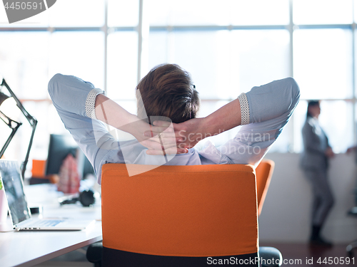 Image of young businessman relaxing at the desk