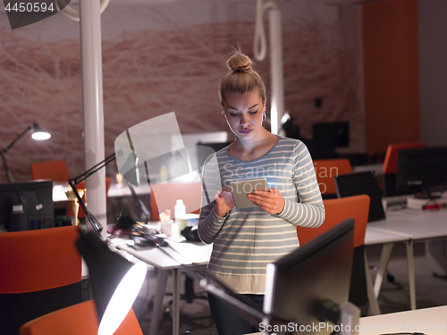 Image of woman working on digital tablet in night office