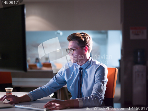 Image of man working on computer in dark office