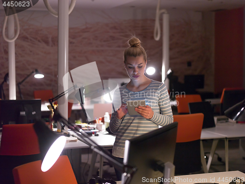 Image of woman working on digital tablet in night office
