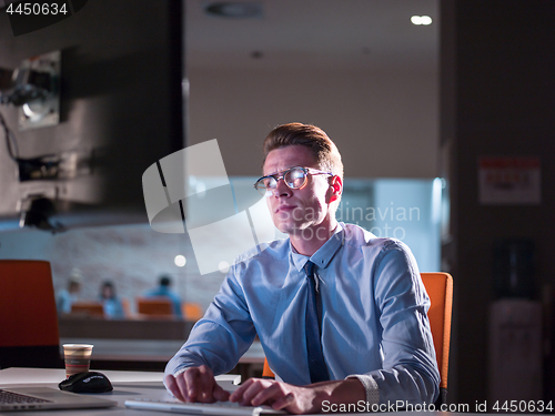 Image of man working on computer in dark office