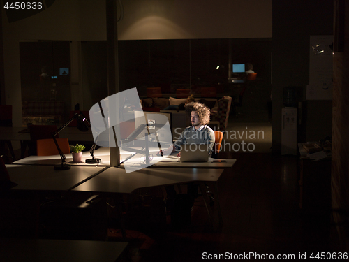 Image of man working on computer in dark office