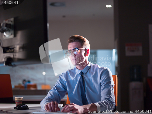 Image of man working on computer in dark office