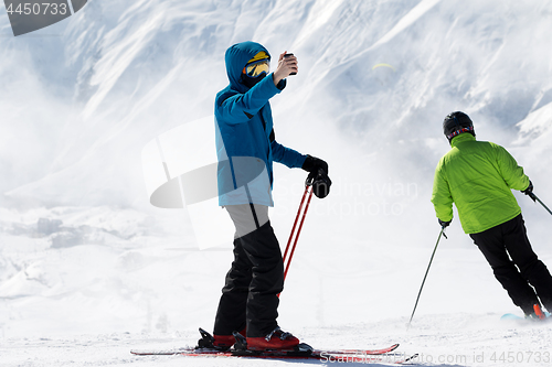 Image of Skier makes selfie on camera phone and snow mountains in fog