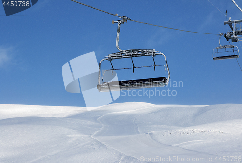 Image of Ski slope, chair-lift on ski resort and blue sky with falling sn