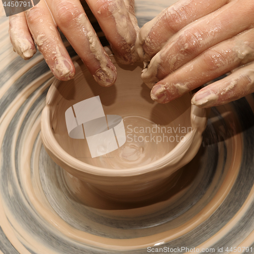 Image of Woman in process of making clay bowl on pottery wheel