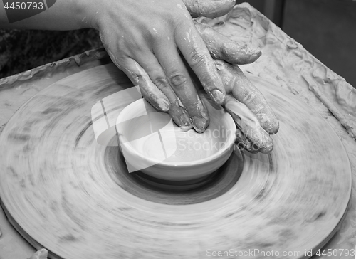 Image of Woman hands in clay at process of making clay bowl on pottery wh