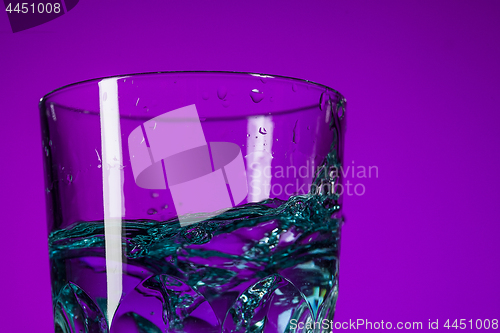 Image of The water splashing in glass on lilac background