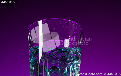 Image of The water splashing in glass on lilac background