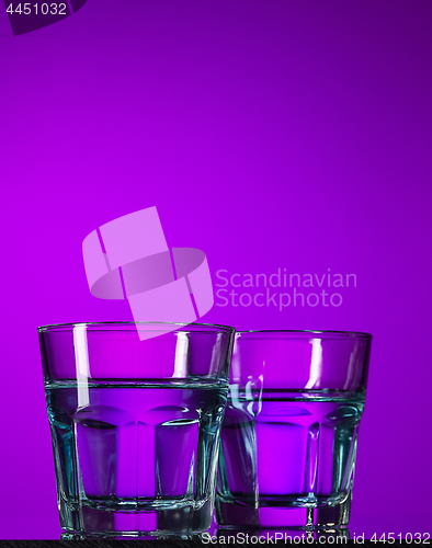 Image of The water in two glassese on lilac background