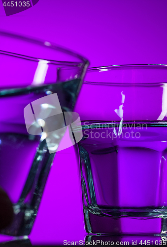 Image of The water in two glassese on lilac background