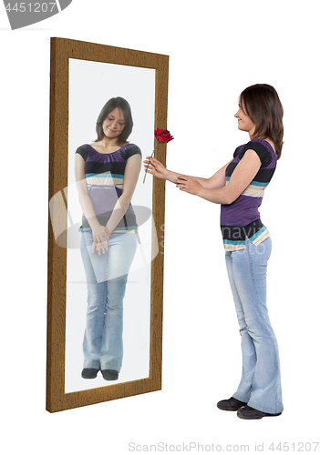 Image of Young woman giving a flower to her reflection in a mirror