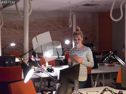 Image of woman working on digital tablet in night office